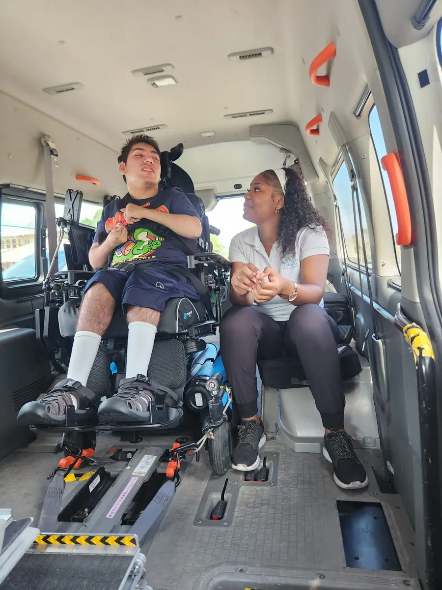 Wellness Express caregiver seated beside a wheelchair user inside the accessible transport vehicle